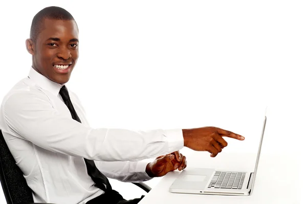 Sonriente joven africano que indica en la pantalla del ordenador portátil — Foto de Stock