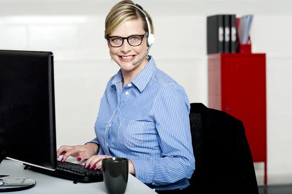 Sorridente help desk donna digitando sulla tastiera — Foto Stock