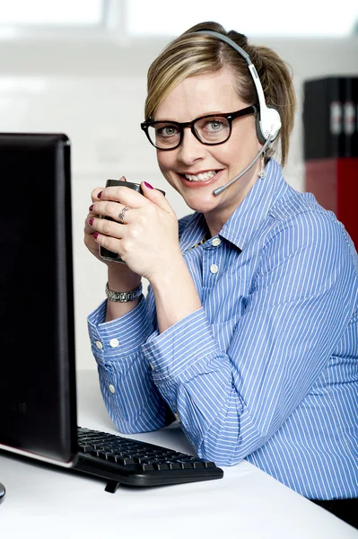 Help desk executive drinking coffee at work — Stock Photo, Image