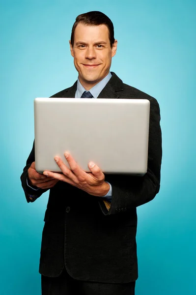 Atractivo empresario sosteniendo portátil — Foto de Stock