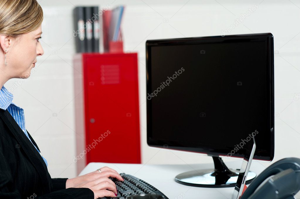 Female executive typing and looking at lcd screen