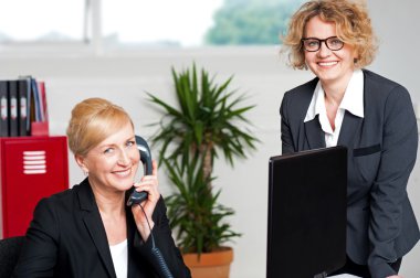 Woman attending call with colleague beside her clipart