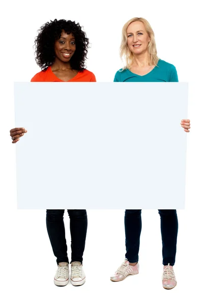 Two young women holding blank billboard — Stock Photo, Image