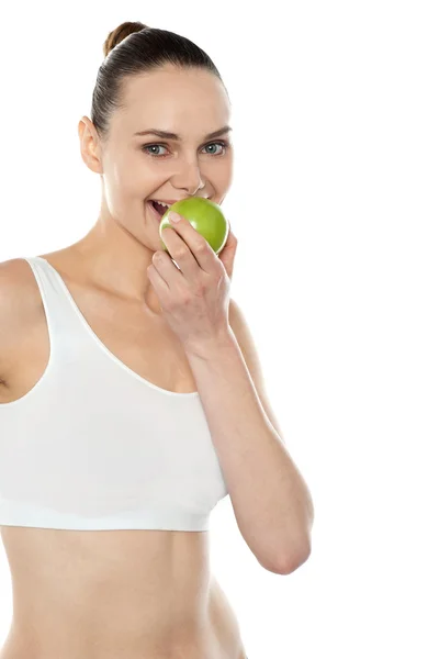 Довольно модная женщина ест свежее зеленое яблоко — стоковое фото