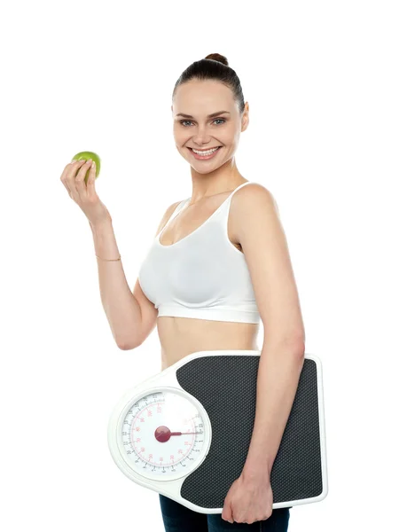 Привлекательная женщина с яблоками и весом — стоковое фото