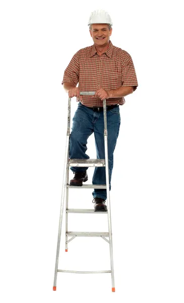 Trabajador con sombrero duro escalando escalera — Foto de Stock