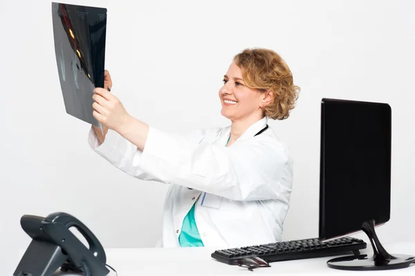 Улыбающаяся женщина-хирург смотрит на пациентов рентгеном — стоковое фото
