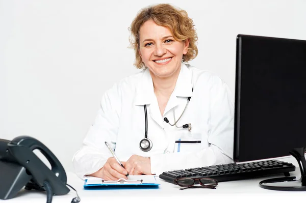 Улыбающаяся женщина-врач средних лет сидит в клинике — стоковое фото