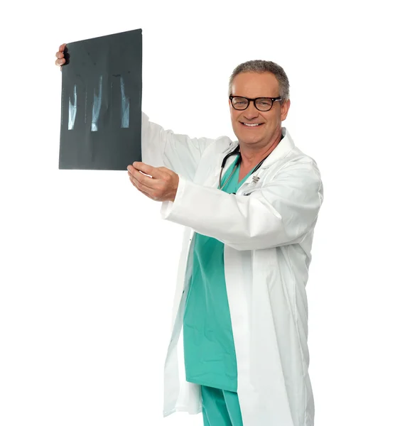 Усміхнений лікар в окулярах розглядає рентгенівський звіт — стокове фото