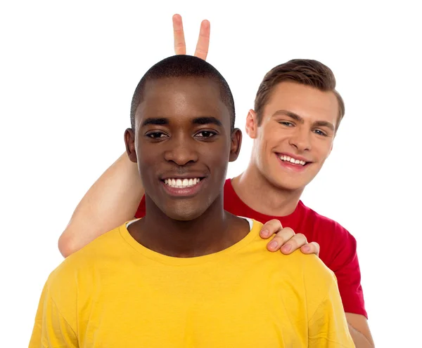 Guy making funny gesture behind his friends head — Stock Photo, Image