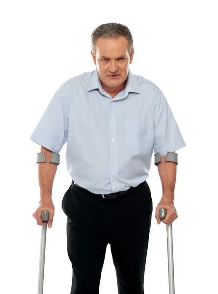 Angry aged man with crutches looking at you — Stock Photo, Image