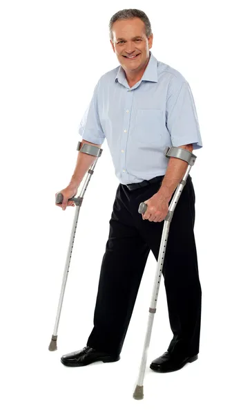Hombre mayor de pie con la ayuda de muletas — Foto de Stock