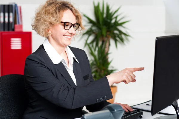 Glad kvinna som pekar på datorskärmen — Stockfoto