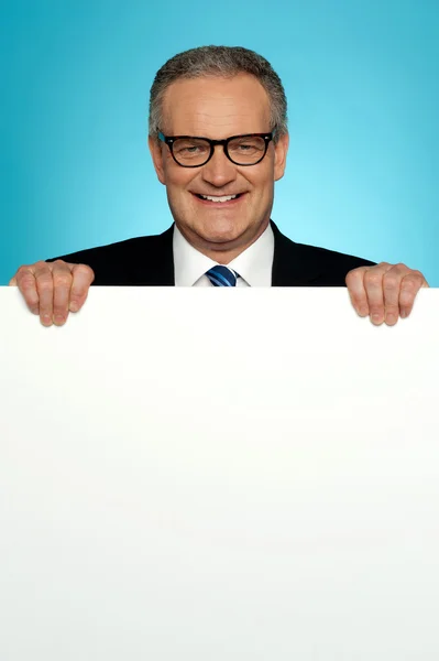 Homem corporativo de pé atrás de grande cartaz em branco — Fotografia de Stock