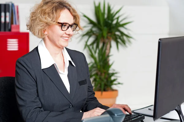 Mulher envelhecida em óculos trabalhando no computador — Fotografia de Stock
