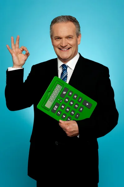Confident executive holding calculator and gesturing okay sign — Stock Photo, Image