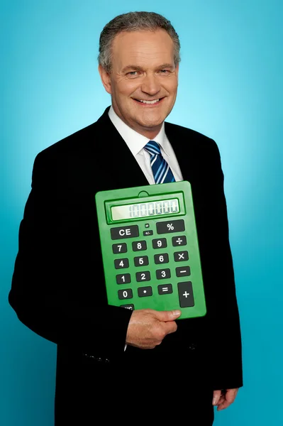 Старший виконавчий позує з великим зеленим калькулятором — стокове фото