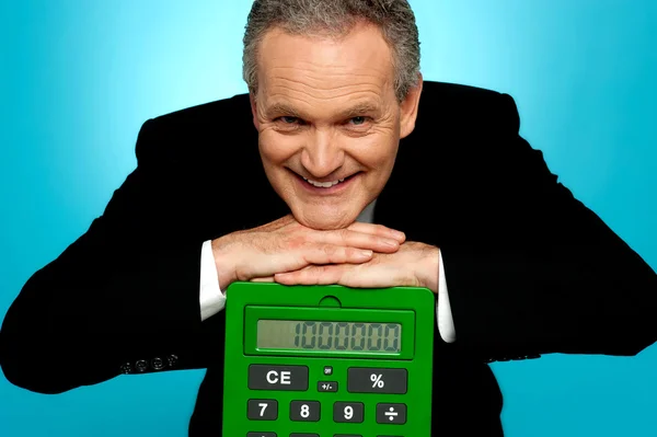 Стареющий корпоративный мужчина, отдыхающий на большом калькуляторе — стоковое фото