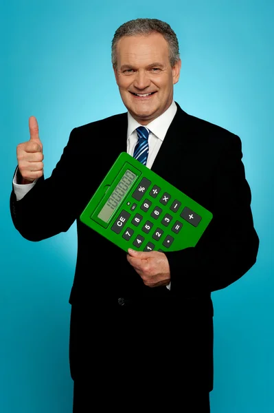 Uomo d'affari mostrando pollici in su, tenendo calcolatrice — Foto Stock