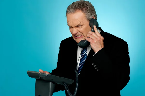 Uomo d'affari irritato che comunica al telefono — Foto Stock