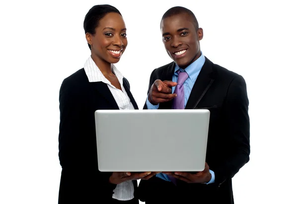 stock image African coworkers operating laptop and pointing