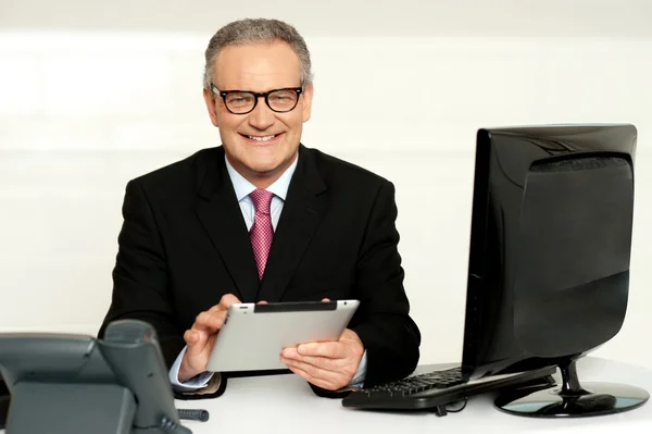 Aged businessman in glasses using tablet — Stock Photo, Image