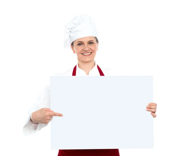 Female chef pointing towards blank whiteboard — Stock Photo, Image