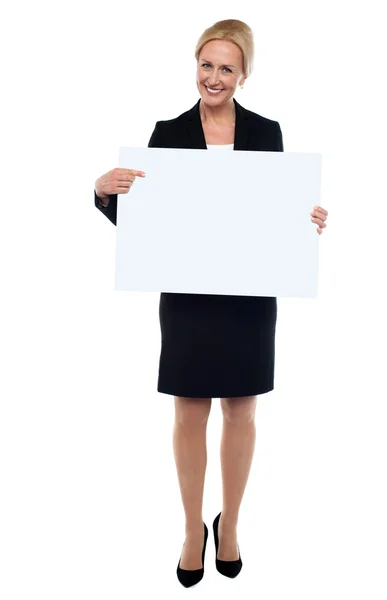 Ejecutivo femenino apuntando hacia el tablero de anuncios blanco — Foto de Stock