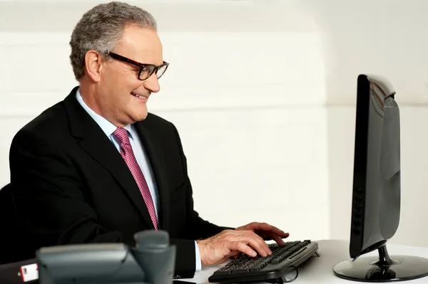 Homme âgé joyeux travaillant sur ordinateur — Photo