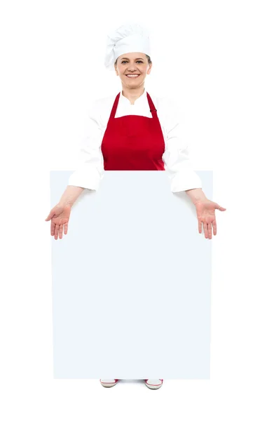 Female cook showing white blank ad board — Stock Photo, Image