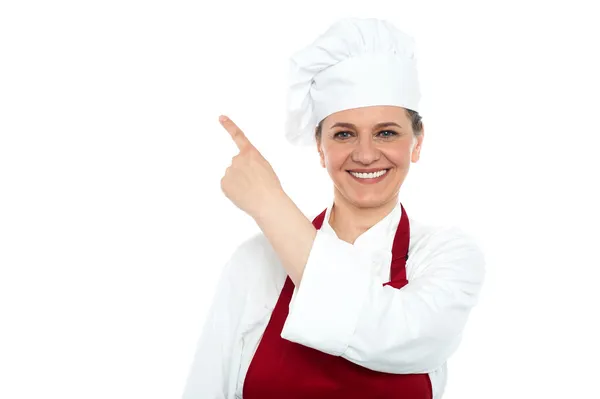 Aged woman chef pointing at copy space area — Stock Photo, Image