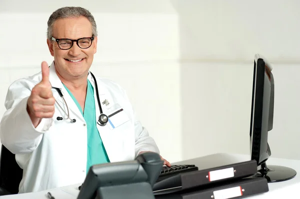 Uśmiechający się lekarz kciuki skrzyżowane do aparatu — Zdjęcie stockowe