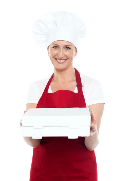 Female baker presenting pizza to you in a box — Stock Photo, Image