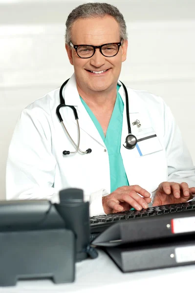 Uśmiechający się lekarza w okulary, wpisując na klawiaturze — Zdjęcie stockowe