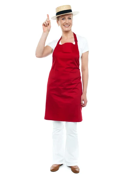 Female chef wearing hat pointing upwards — Stock Photo, Image