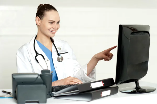 Especialista médica apontando para a tela do computador — Fotografia de Stock