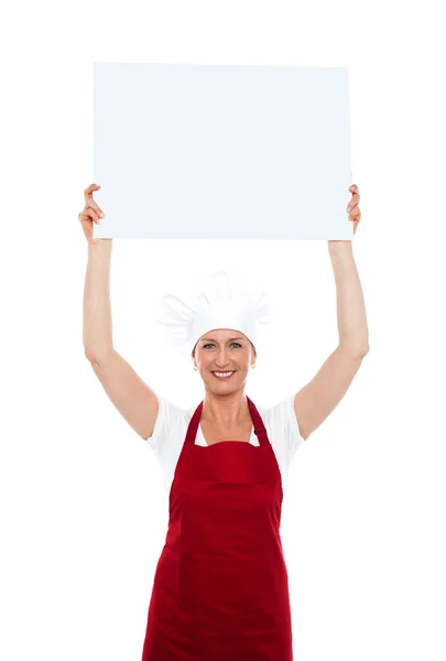 Chef sosteniendo un cartel publicitario sobre su cabeza — Foto de Stock