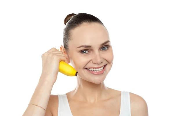 Девушка делает жест вызова, используя банан в качестве мобильного телефона — стоковое фото