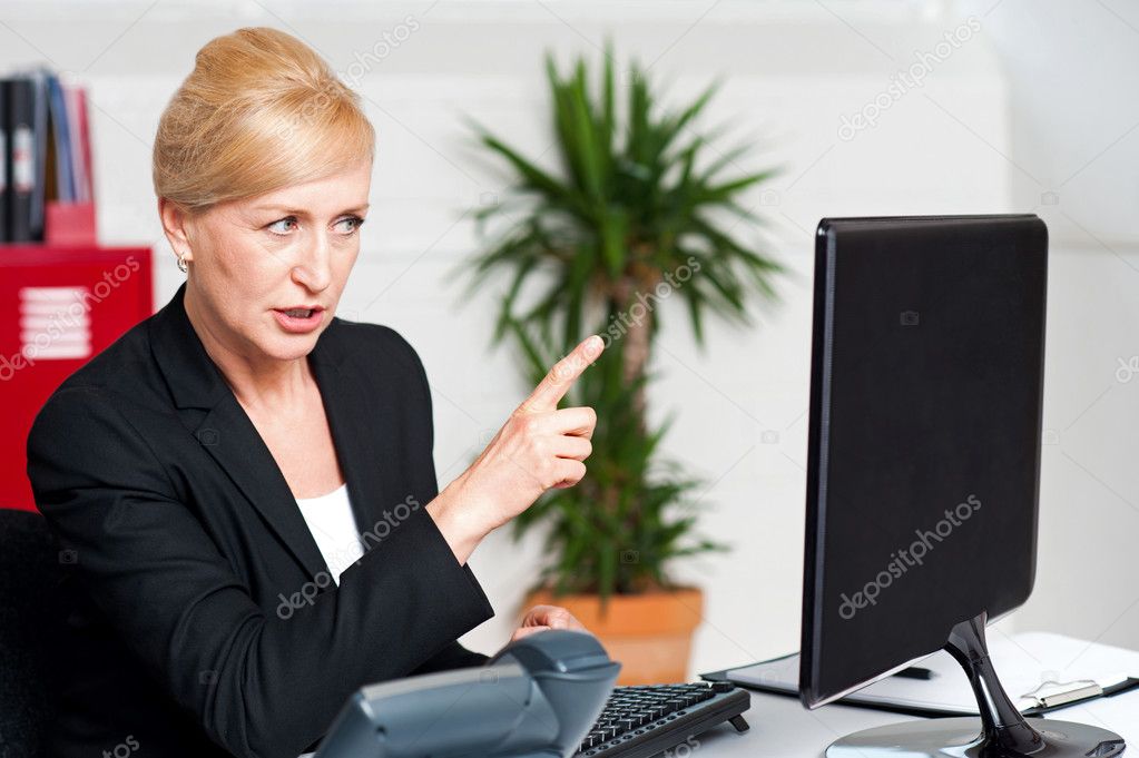 Angry woman indicating at computer led screen