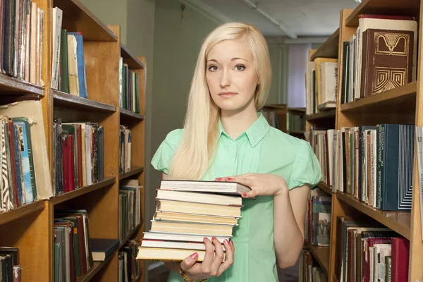 Female university student holding books in library — Stock Photo, Image
