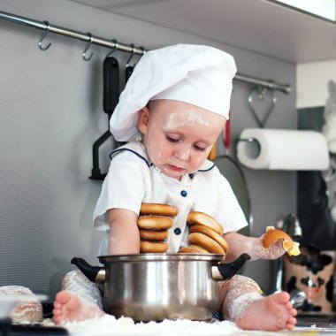 Portrait of a baby wearing a chef hat sitting inside a large cooking stock pot clipart