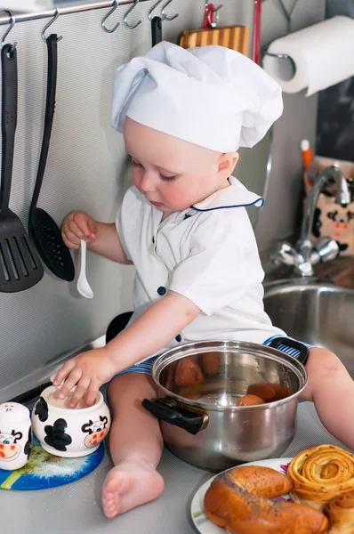 Porträt eines Babys mit Kochmütze, das in einem großen Kochtopf sitzt — Stockfoto