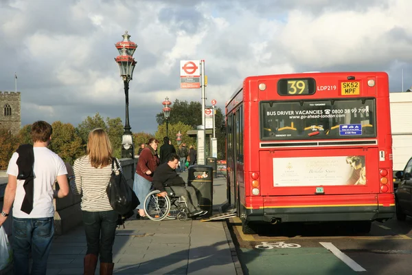 Un hombre en silla de ruedas subiendo a un autobús público — Foto de Stock
