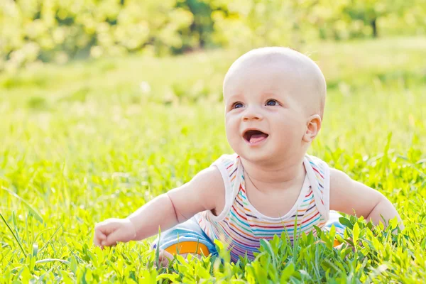 Happy laughing baby sitting on the grass — Stock Photo, Image