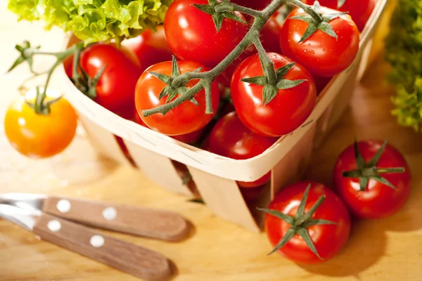 Sałatka w kosz na drewnianym stole i pomidorów — Zdjęcie stockowe