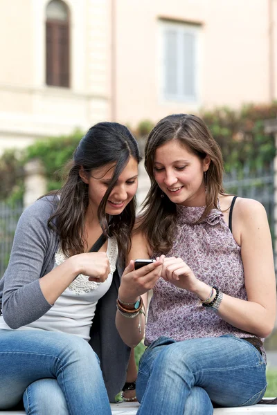 Deux copines dans le parc avec un téléphone portable Images De Stock Libres De Droits