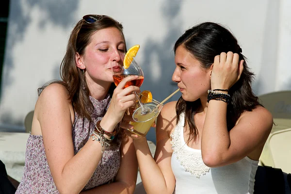 Dos mujeres jóvenes animando con bebidas frías — Foto de Stock