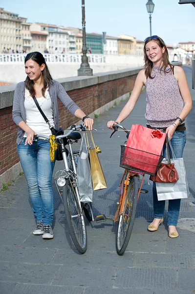 Δύο όμορφες γυναίκες που περπατούν στην πόλη με ποδήλατα και τσάντες — Φωτογραφία Αρχείου