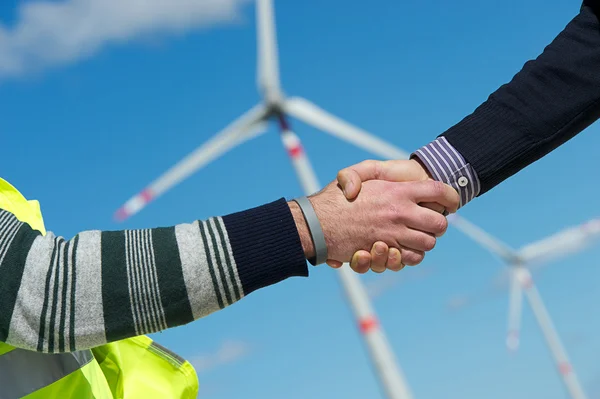 Інженери, даючи рукостискання в електростанція вітрових турбін — стокове фото
