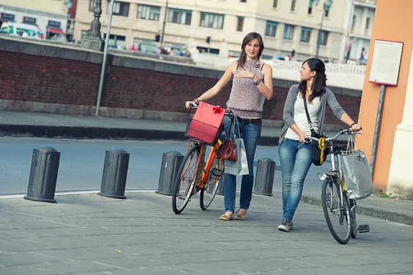 Дві красиві жінки ходять містом з велосипедами і сумками — стокове фото